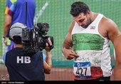 احسان حدادی شعر نوشته شده بر روی پیراهن خود را به تصویربردار مسابقات نشان می‌دهد